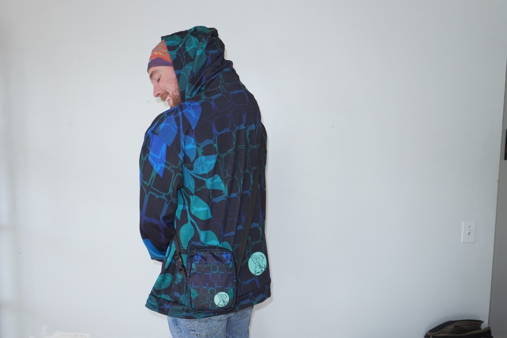 Model in a vibrant gradient hoodie, standing against a textured backdrop.