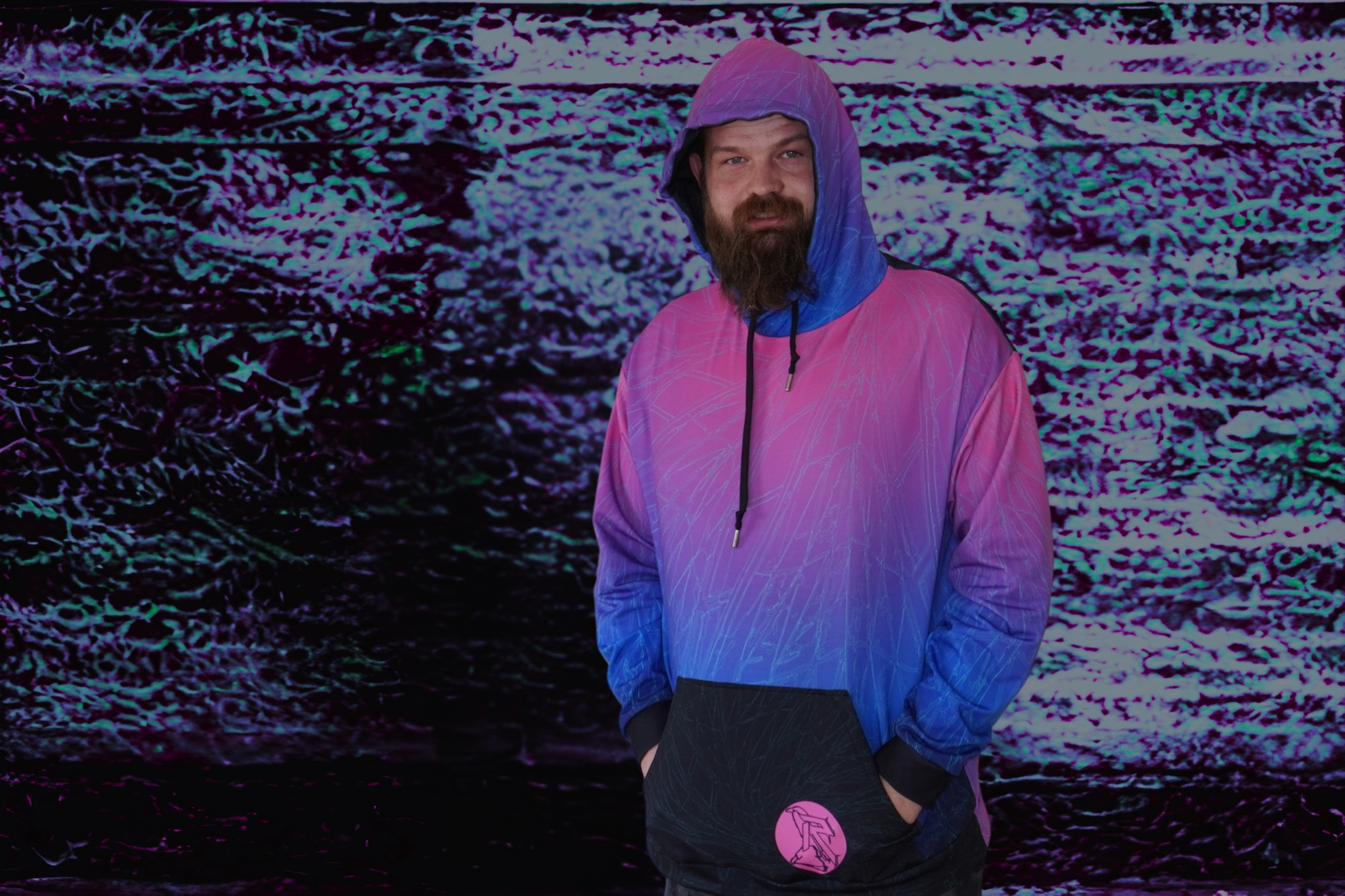 Model in a pink and blue gradient hoodie against a neon, textured background.