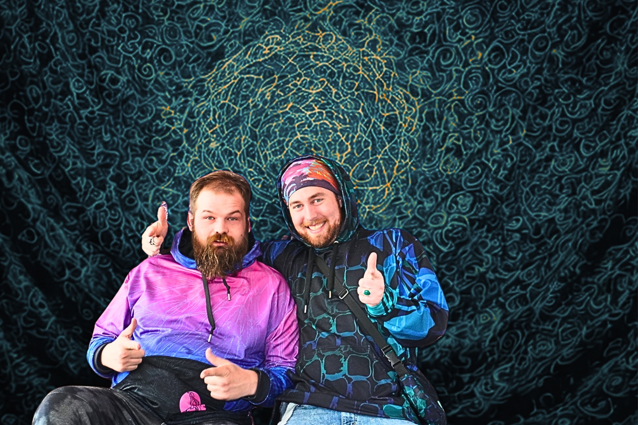 Two friends posing in vibrant festival hoodies, with a swirling, trippy background.
