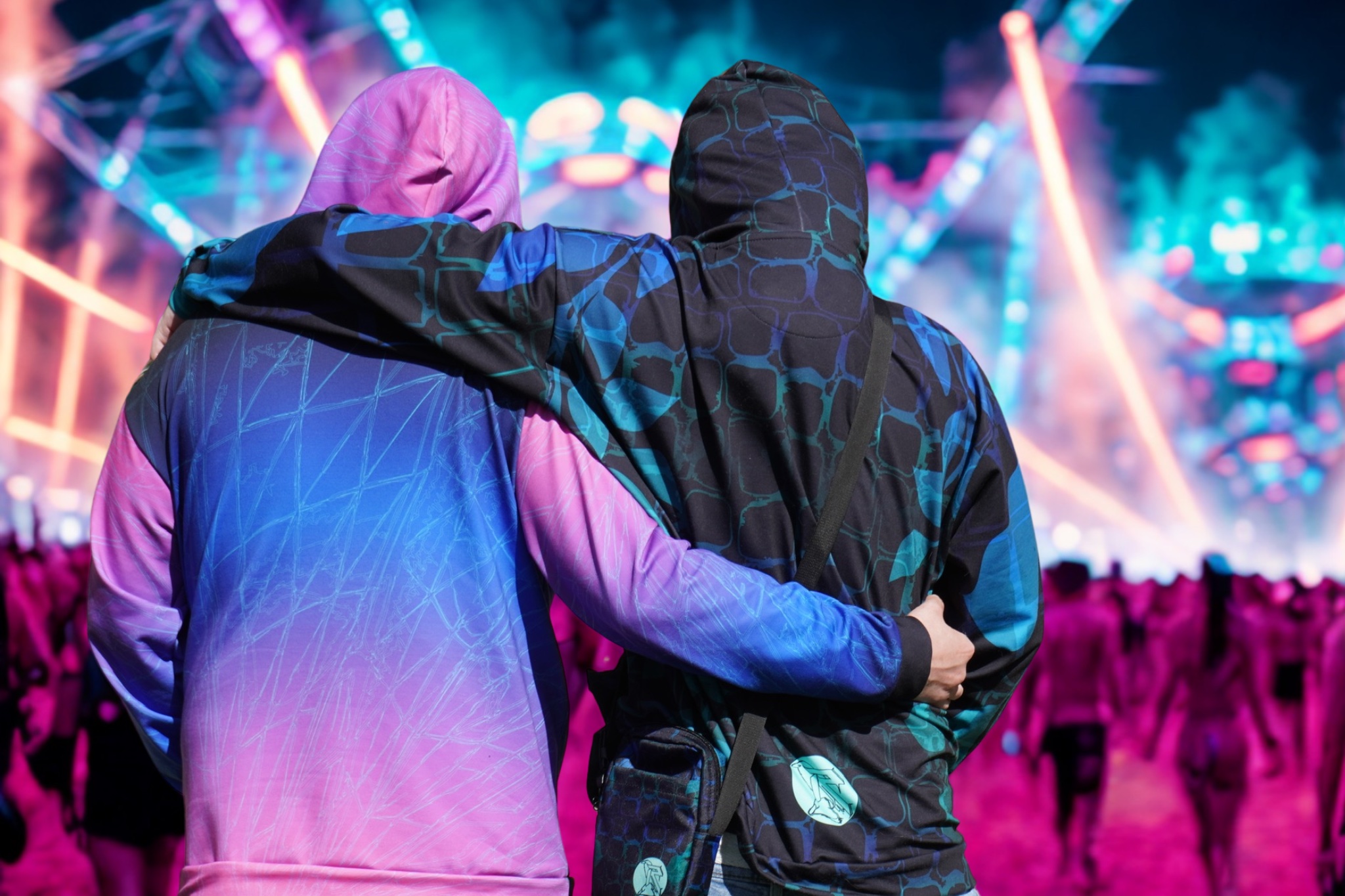 Vibrant RavenRock hoodie with a neon-lit background, showcasing the back design with electric blue and pink patterns.